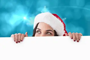 Santa Hat Prints: Pretty brunette in santa hat showing white poster against blurred christmas background