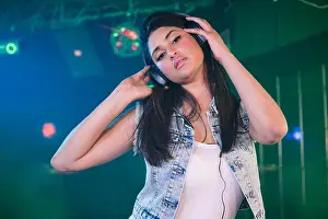 Nightclub Prints: Pretty female DJ listening music on headphone