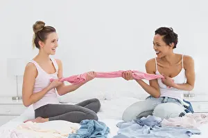 Pajamas Prints: Pretty friends jokingly fighting over clothes on bed