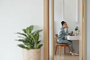 Pajamas Prints: Pretty woman in silk pajamas applying make-up in front of mirror at her vanity