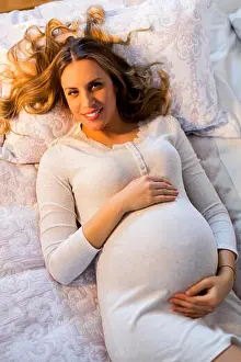 Lying Prints: Pretty young pregnant woman lying on the bed in room
