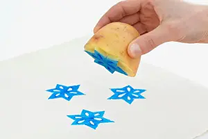 Printing star shapes onto white paper using potato print technique
