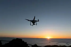 Hovering Prints: Professional Drone flying at Sunrise over the sea. The sky is glowing