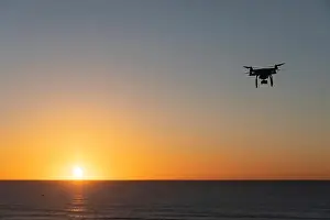 Hovering Prints: Professional Drone flying at Sunrise over the sea. The sky is glowing