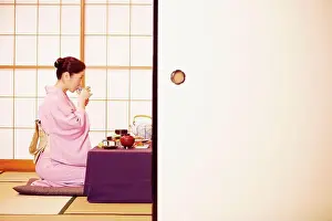 Kneeling Prints: Side profile of a mature woman wearing a Kimono and drinking from a cup