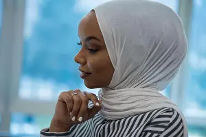Thinking Prints: A side profile portrait of a young Muslim woman wearing a white hijab and a striped blouse