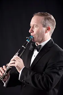 Tuxedo Prints: Profile shot of man in tuxedo playing clarinet over black background