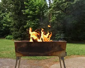 Flames Prints: Public outdoor charcoal grill in the summer park with wood ashes and fire flames preparing for grilling