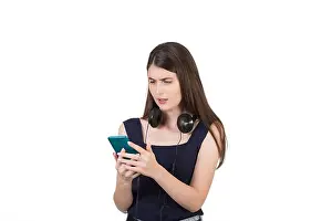 Puzzled Prints: Puzzled young woman with headphones looking confused at her smartphone