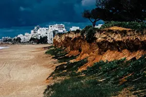 Waters Edge Prints: Quarteira Beach in Quarteira, Algarve, Portugal on a cloudy day - erosion next to beach