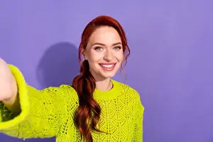 Redhead Prints: Radiant young woman with red hair in vibrant green knit sweater smiling against a bright purple backdrop
