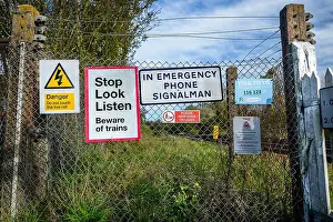 Prohibited Prints: Railroad crossing warning signs on fence at countryside level crossing