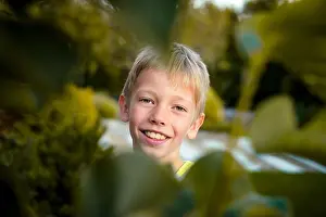 Hiding Prints: RAJHRAD, CZECH REPUBLIC - Nov 02, 2020: Small kid, boy, behind the leaves is smiling