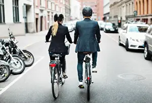 Couple Relationship Prints: Rear view of business people riding bicycles on street