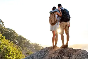 Mountain Peak Prints: Rear view of hiking couple with backpack standing together on hill top enjoying beautiful landscape
