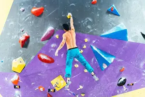 Rear View Prints: Rear view of man ascending rock climbing wall