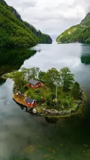 Green Trees Prints: A red cabin nestled on a small island in a fjord surrounded by green mountains and calm water