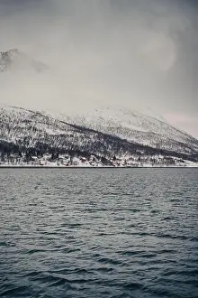 Red cabins by the arctic ocean below Lyngen Alps mountains in northern Norway