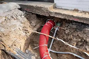 Flexible Prints: Red corrugated pipe are buried underground on the street made for electric cable infrastructure installation