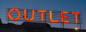 Pants Prints: Red glowing neon Outlet store sign on Turkish bazaar building with night sky in the background
