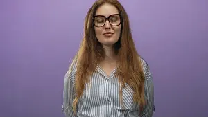Eyelid Prints: Red haired woman wearing glasses and striped shirt blinks eyes and smiles gently in studio; calm confidence