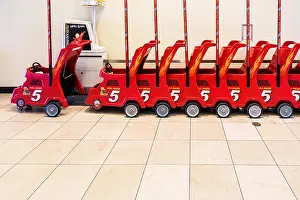 Shopping Center Prints: Red rental child strollers lined up in a shopping mall in Oklahoma City