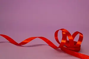 Satin Prints: Red satin ribbon curls on a lilac background, free space