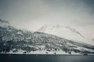 Whale Watching Prints: Red wooden cabins in the snowy Lyngen Alps by the arctic ocean in Norway