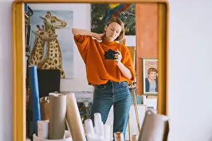 Mid Adults Prints: Reflection of woman holding camera on mirror at art studio