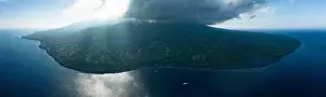 The remote, volcanic island of Sangeang rises from the seascape near Komodo National Park, Indonesia. This island is known for its black sand habitat