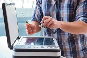 Screwdriver Prints: Repairman repairing broken color printer