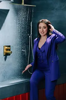 Eccentric Prints: Representative saleswoman in purple suit testing overhead shower, water running