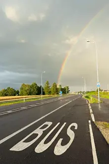 Road Travel Prints: Road with bus lane marking under rainbow after rain in Estonia