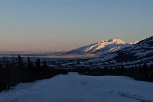 Caribou Prints: Road next to Donnelly Dome with sun shining on mountain in the background on a winter afternoon near Delta Junction