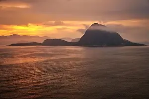 Rock Hessa nearby Alesund/Norway in the ocean with clouds in sunrise
