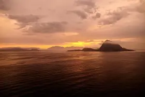 Rock Hessa nearby Alesund/Norway in the ocean with clouds in sunrise