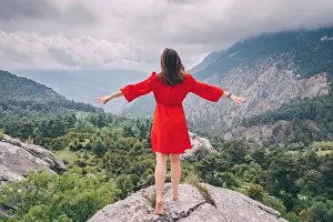 Sky Island Prints: Romantic aerial photo of a girl in a red dress on top of a cliff admiring the view of a mountain gorge
