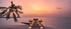 Images Dated 11th December 2018: Romantic dinner on the beach with sunset, candles with palm leaves and sunset sky and sea