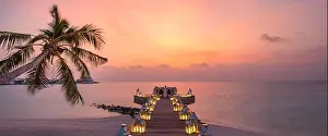 Romantic dinner on the beach with sunset, candles with palm leaves and sunset sky and sea. Amazing view, honeymoon or anniversary dinner landscape