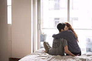 Falling In Love Prints: Romantic lesbians embracing while sitting on bed at home