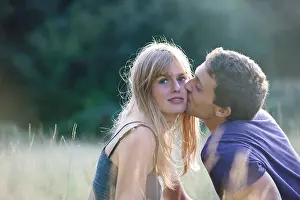 Intimacy Prints: A romantic young couple outdoors, man kissing the womans cheek