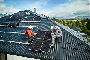 Coworkers Prints: Roofers building photovoltaic solar module station on roof of house