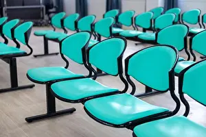 Lobby Prints: A row of empty turquoise plastic chairs with black metal frames in waiting area