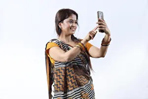 Saree Prints: Rural Indian happy woman in saree taking selfie and doing a video call in a village