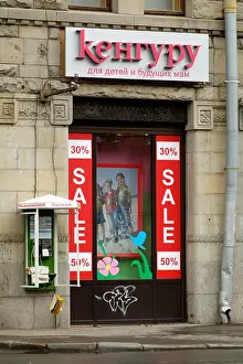 Russian Federation Prints: Russian Childrens Clothing Shop Sale and a wall mounted public telephone in St Petersburg Russia