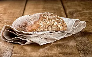 Oats Prints: Rustic bread loaf with oats served on napkin on a wooden table