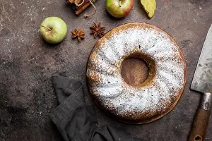 Moist Prints: Rustic Style Apple Bundt Cake Sprinkled with Icing Sugar on old wooden table, top view