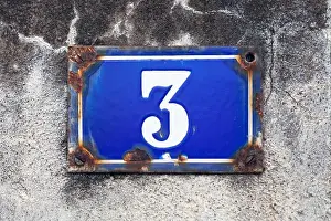 Wall Building Feature Prints: Rusty blue street plate on a white wall with a number 3 painted in white in the middle