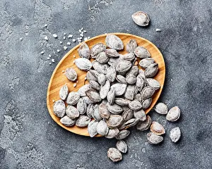 Salted Prints: Salted apricot seeds on grey background. Apricot bones fried with salt in ashes