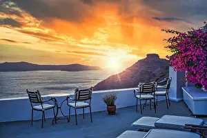 Santorini island sunset. Caldera view with chairs and flowers, romantic mood, couple travel vacation landscape destination scenic. Tourism romance